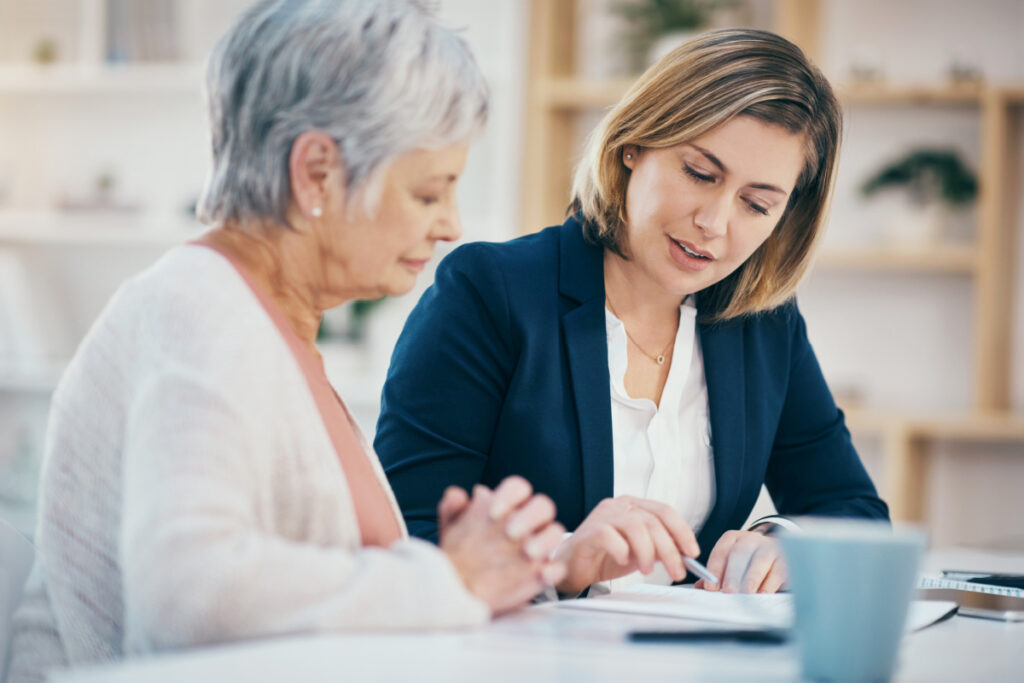 Senior woman signing paperwork with estate planning lawyer